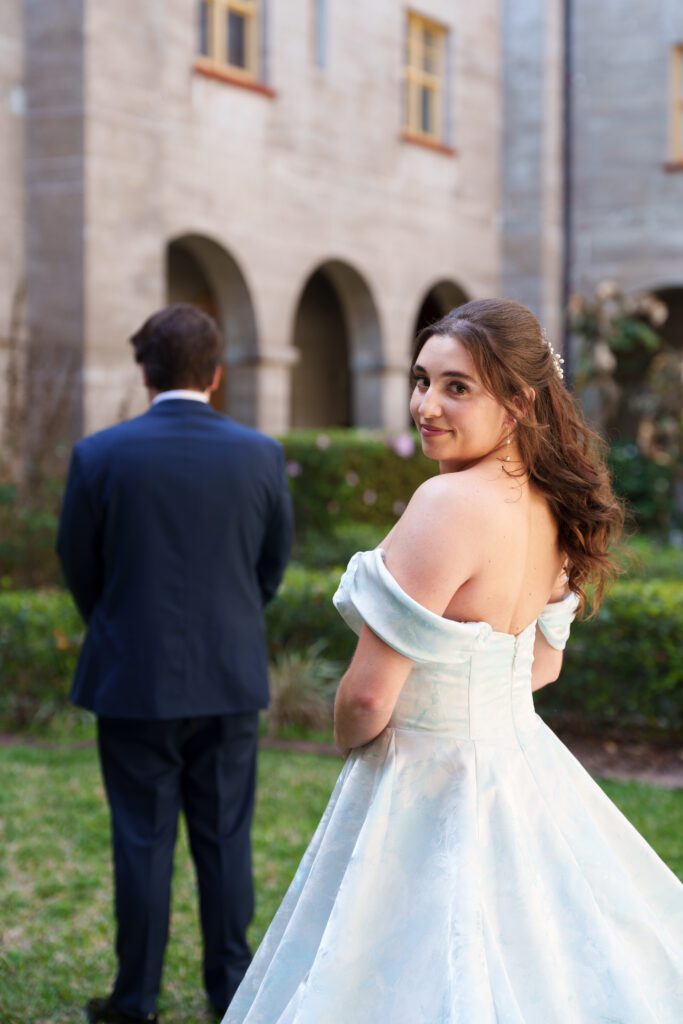 Bride tapping groom for first look at Lightner Museum courtyard St Augustine Florida wedding