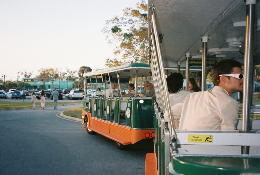 Wedding guests riding St Augustine trolley from ceremony to Lightner Museum reception destination wedding Florida