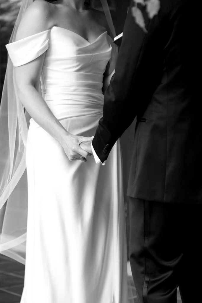 Close view of a bride and groom's clasped hands during their private vow exchange