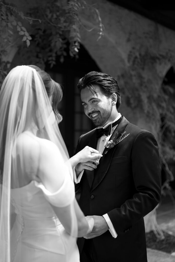 Groom smiling at his bride as they hold hands during their first look at Villa Parker