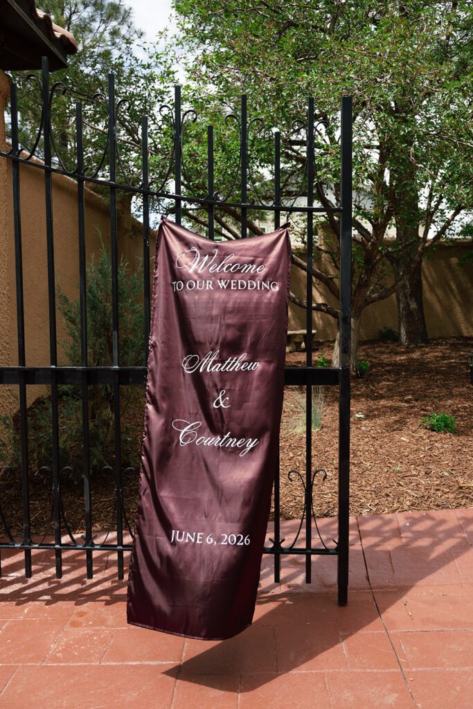 Burgundy welcome banner hanging from an iron gate at Villa Parker