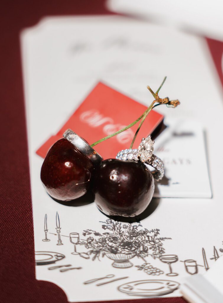 Wedding rings resting on two cherries beside a hand-drawn dinner menu