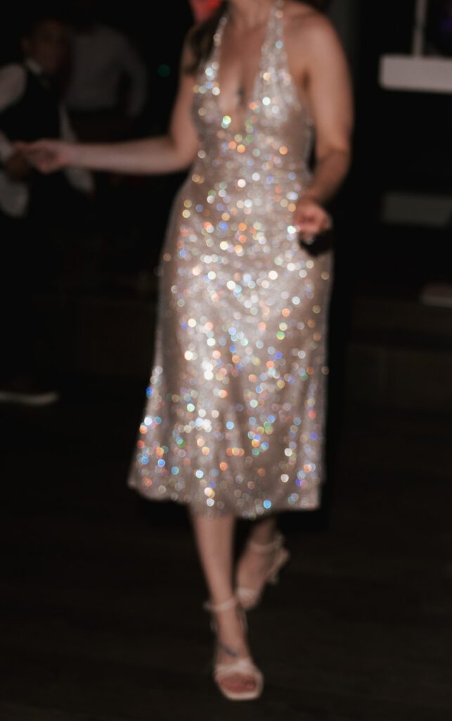 Bride dancing in a sparkling silver halter midi dress during the reception