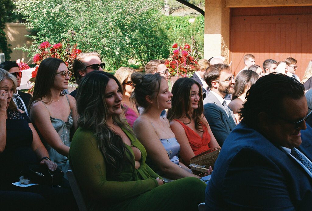 Wedding guests watching the ceremony beside the red floral fountain at Villa Parker